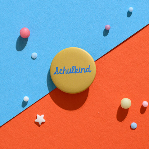 Button „Schulkind“, blau mit Hintergrund senf
